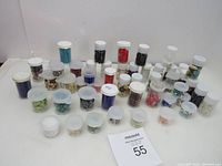 Wide view of all 50 small containers of mixed beads arranged on a white surface to show quantity and variety.
