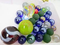 Top view of 30 marbles in a white container showing variety of colors, sizes, and finishes