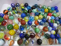 Top-down view of 115 glass marbles in a plastic container showing colorful variety
