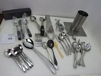 Photo showing various kitchen utensils including a beer can roaster, espresso spoon, condiment spoons, and mixed cutlery.