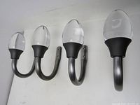 Four Umbra curtain tiebacks with solid glass ends shown mounted on a white wall background. Shows front view of their clear glass finials and metal hooks.