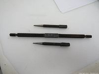 Photo of the thread file and two center punches lying horizontally on a light surface.