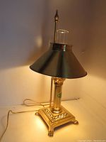 Full view of the vintage brass Orient Express table lamp, showing the square base, central column, and conical adjustable shade with the chimney on top.