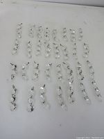 Lot image showing all 31 strings of vintage clear glass crystals chains laid out on a flat surface, connected with brass wire connectors.