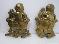 Front view of both vintage brass bathroom wall plaques, boy and girl figures, showing detailed relief design and brass finish.