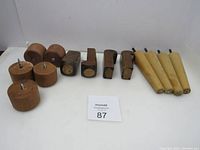 Photo showing 3 sets of wooden furniture legs arranged in a line, including round, tapered, and rectangular legs with screws attached.