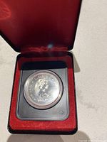 Obverse side of the 1977 Silver Jubilee Canadian silver dollar showing Queen Elizabeth II's portrait in a protective plastic capsule inside a red velvet lined case.
