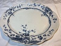 Overhead view of oval ceramic platter with blue floral and ornamental decoration on white background.