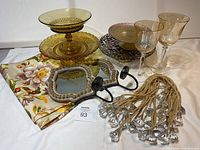 Photo of assorted cake stands, footed dishes, amber glass goblets, floral tablecloth, mirror candle sconces, and decorative tiebacks.