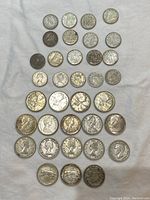 Full lot of 35 Canadian silver coins including 17 quarters and 18 dimes displayed face up on a white cloth background.