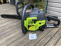 Full view of Poulan chainsaw showing body, handle, and bar with chain on wooden surface.