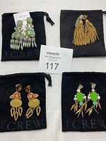 Four pairs of J Crew statement earrings on black fabric pouch with auction tag.