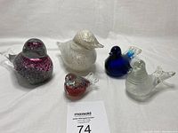 Lot of five glass birds arranged in a row showing shape and color variety.