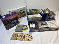 Full lot with CDs, DVDs, Blu-rays, puzzles, and antique playing cards on display.