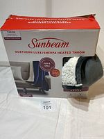 Box packaging of the Sunbeam Northern Luxe Sherpa Heated Throw blanket with product image and branding visible.
