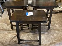 Set of three dark finished wood counter height stools showing overall wear and construction details.