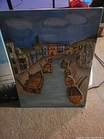 Painting depicting a canal at night with boats and old buildings along the shore, dark sky background.