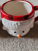 Close-up of ceramic Frosty the Snowman mug showing white face, orange carrot nose, and red hat rim