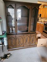 Full front view of the china cabinet showing top glass display doors and bottom cupboard doors in a kitchen setting.