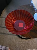 Top view of large red translucent plastic fruit dish with a fluted or scalloped edge design