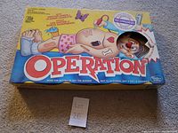 Photo of Operation game box placed on carpet, showing the front artwork and condition of the box.