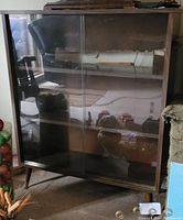 Front view of the retro wooden bookcase showing the two sliding glass doors and wooden frame reflecting surroundings.