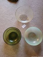 Photo showing three glass bowls together: one clear with floral etching, one olive green textured, and one light green translucent.
