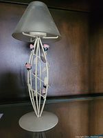 Full view of decorative tea light lamp showing metal base and frosted glass shade with pink flower details on metal branches