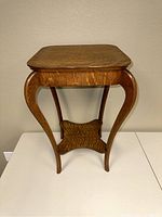 Front view of the wood accent table, showing the square top and curved legs.