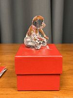 Clear crystal teddy bear figurine sitting on a red Baccarat box showing front side and detail.