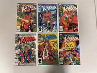 Top view showing six The Uncanny X-Men comic book covers arranged in two rows of three on a white surface.