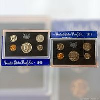 Front view of 1968 and 1971 United States Proof Sets showing obverse sides of coins and blue labels with respective years.