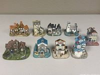 Photo showing all nine house figurines arranged in two rows, clearly displaying variety in architectural design and colors.