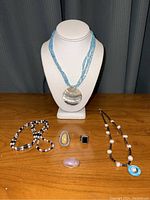 Full lot display with all necklaces and rings arranged on table and display bust