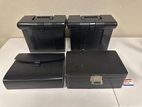Two black plastic file boxes and two black office organizers shown closed on table.
