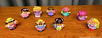 Photo showing all 10 Little People toy figures arranged in two rows on wooden surface.
