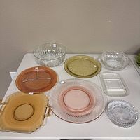 Eight glass plates and dishes of various shapes and colors including amber, pink and clear.