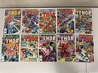 Photo showing all 10 Thor comic books side by side on a flat surface, displaying colorful covers with various Thor comic scenes and Marvel Comics Group branding.