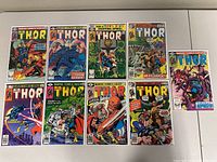 Nine Thor comic books laid out side by side, showing colorful vintage covers featuring Thor in action scenes, posing, and fighting various foes.