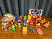 Group of various children's toy figures including McDonald's, Little People boats and vehicles, and a boxed Maisto motorcycle model