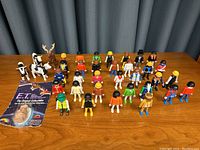 Full view of 26 LEGO-style toy figures arranged on table alongside unopened packaged E.T. collectible figure