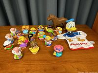 Full group view showing all 18 small children figures, wooden horse, and hand puppet on a table.