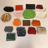 Group layout of the entire lot of sixteen coin purses, showing various shapes, colors, and materials.