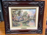 Front view of the framed artwork showing the lake scene with houses and nature.