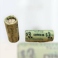 Photo showing two paper rolls of $3 dimes, labeled with Harrah's Casino branding and denomination markings.