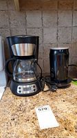PC 5 cup drip coffee maker with glass carafe and electric milk frother on kitchen counter.