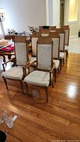 Full view of 8 wood dining chairs with fabric seats and backs, including 2 captain chairs with armrests, displayed on hardwood floor.