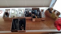 Wide view of all shoe boxes on a table showing an assortment of ladies flats and heels size 7