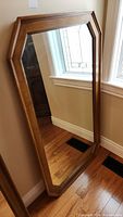 Full-length view of the wood framed mirror leaning against wall