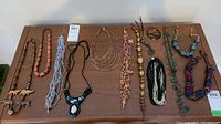 Image showing ten assorted necklaces laid out on a wooden surface